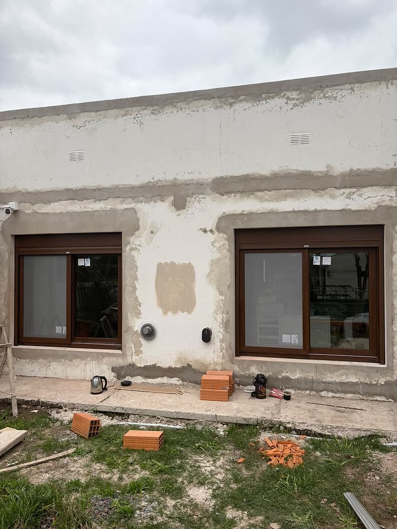 Dos ventanas símil madera en una fachada
